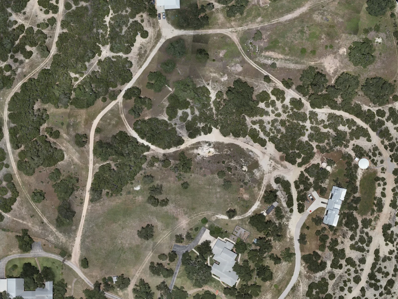 The showcase ranch straight down from the flight: a house, its drive, live oaks and cedar